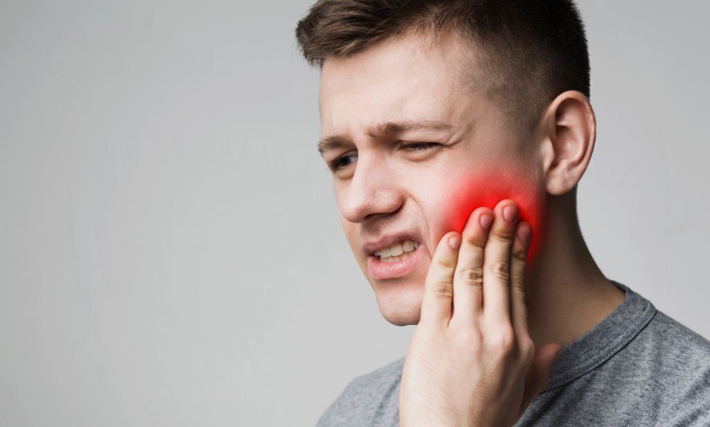 Frustrated young man touching his tooth