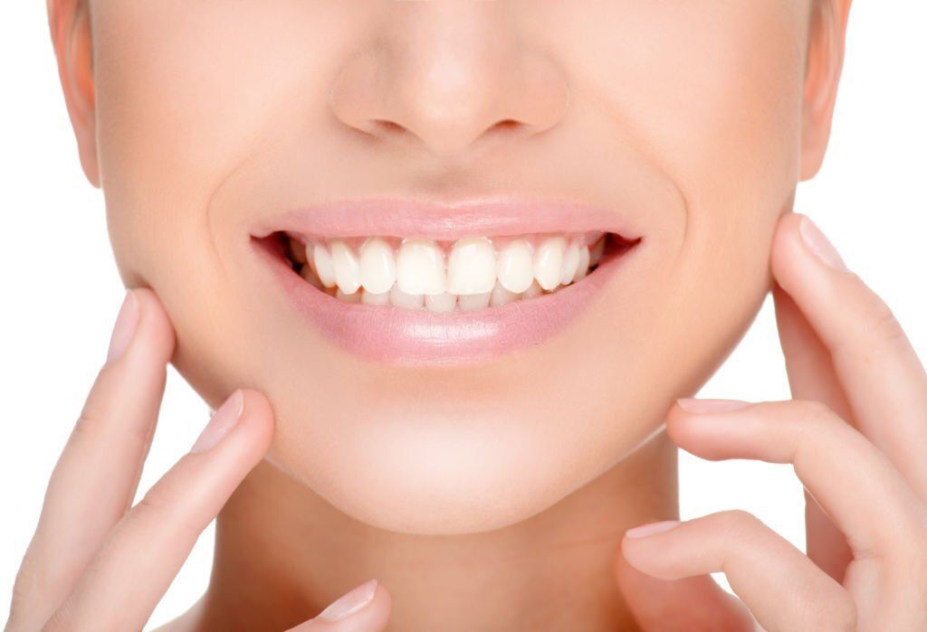 A close-up of a person smiling, with hands held gently to both sides of their face.
