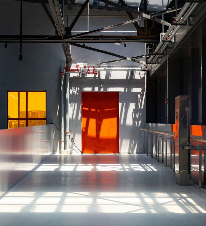 Sunlit modern interior with orange door and window, beams casting grid-like shadows on white floor
