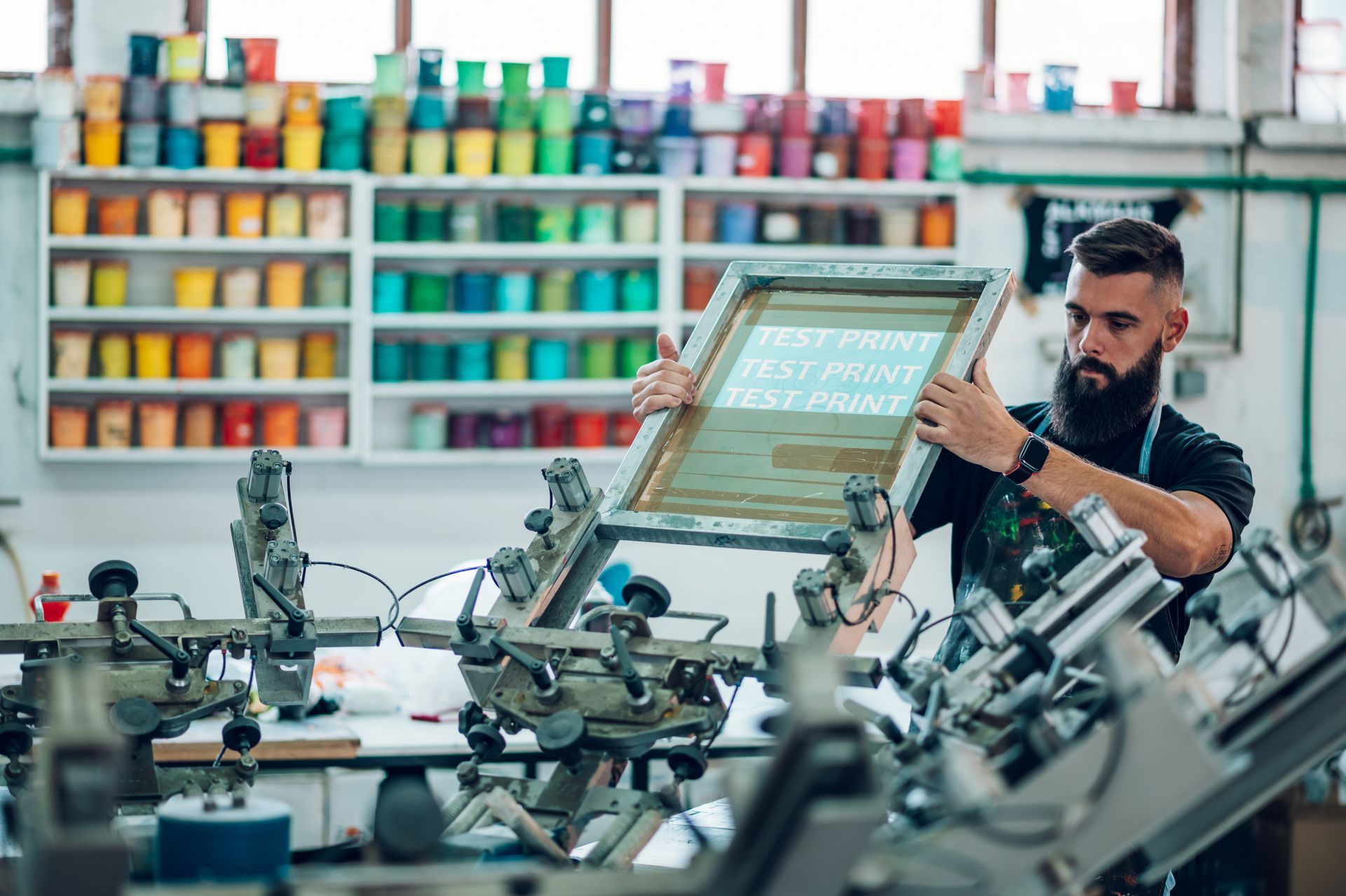 Male worker preparing screen printing film in a workshop.