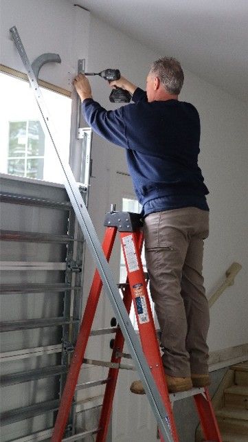 Technician installing garage door hardware during residential service indoors.