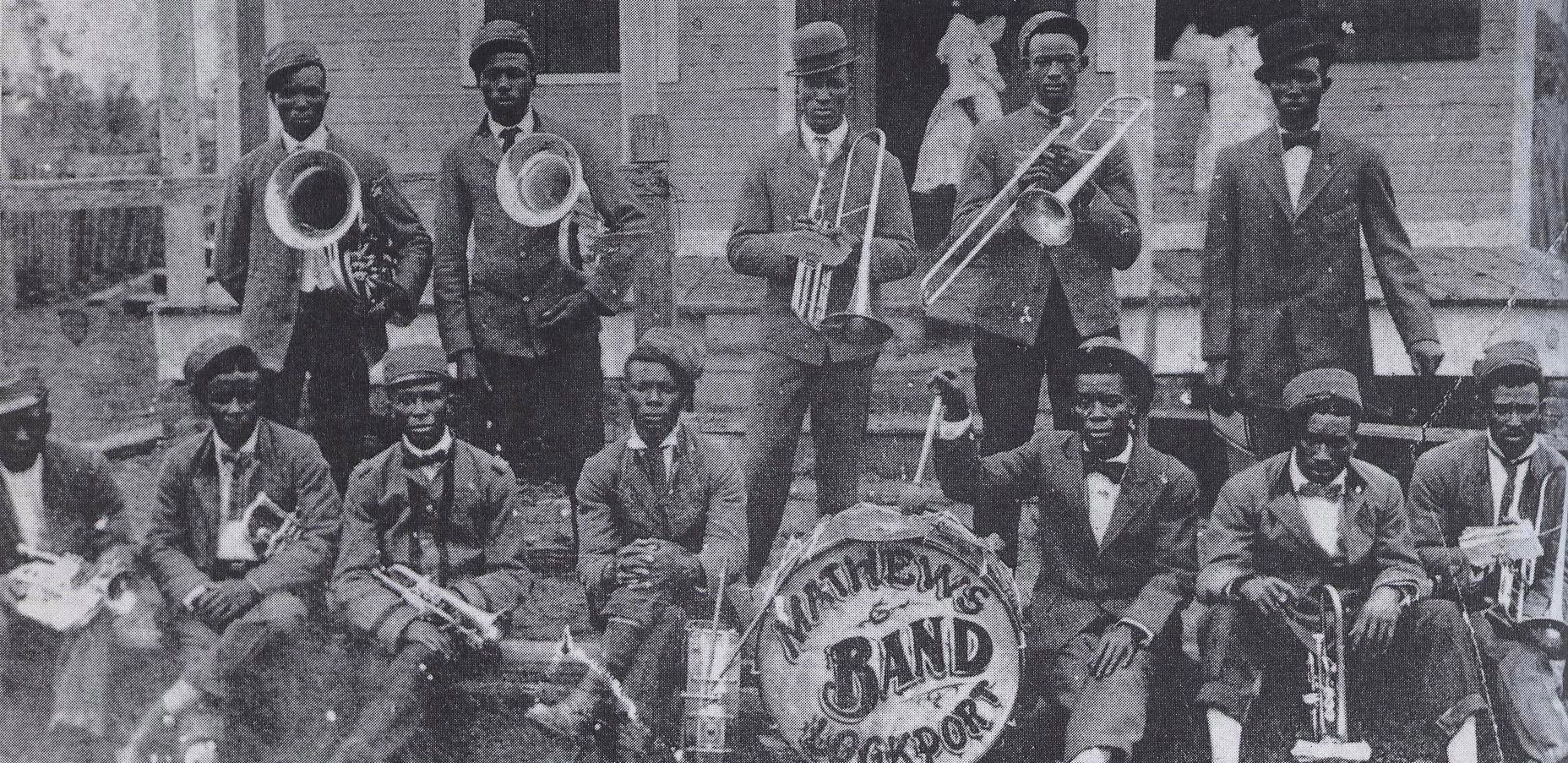 The Mathews Band of Lockport, Louisiana, 1904. Note brass band instrumentation with brass, plus snare and bass drum; no reeds. Slide and valve trombone.
Historic photograph by an uncredited photographer, reproduced from New Orleans Jazz: A Family Album by Al Rose and Edmond Souchon. Public domain.