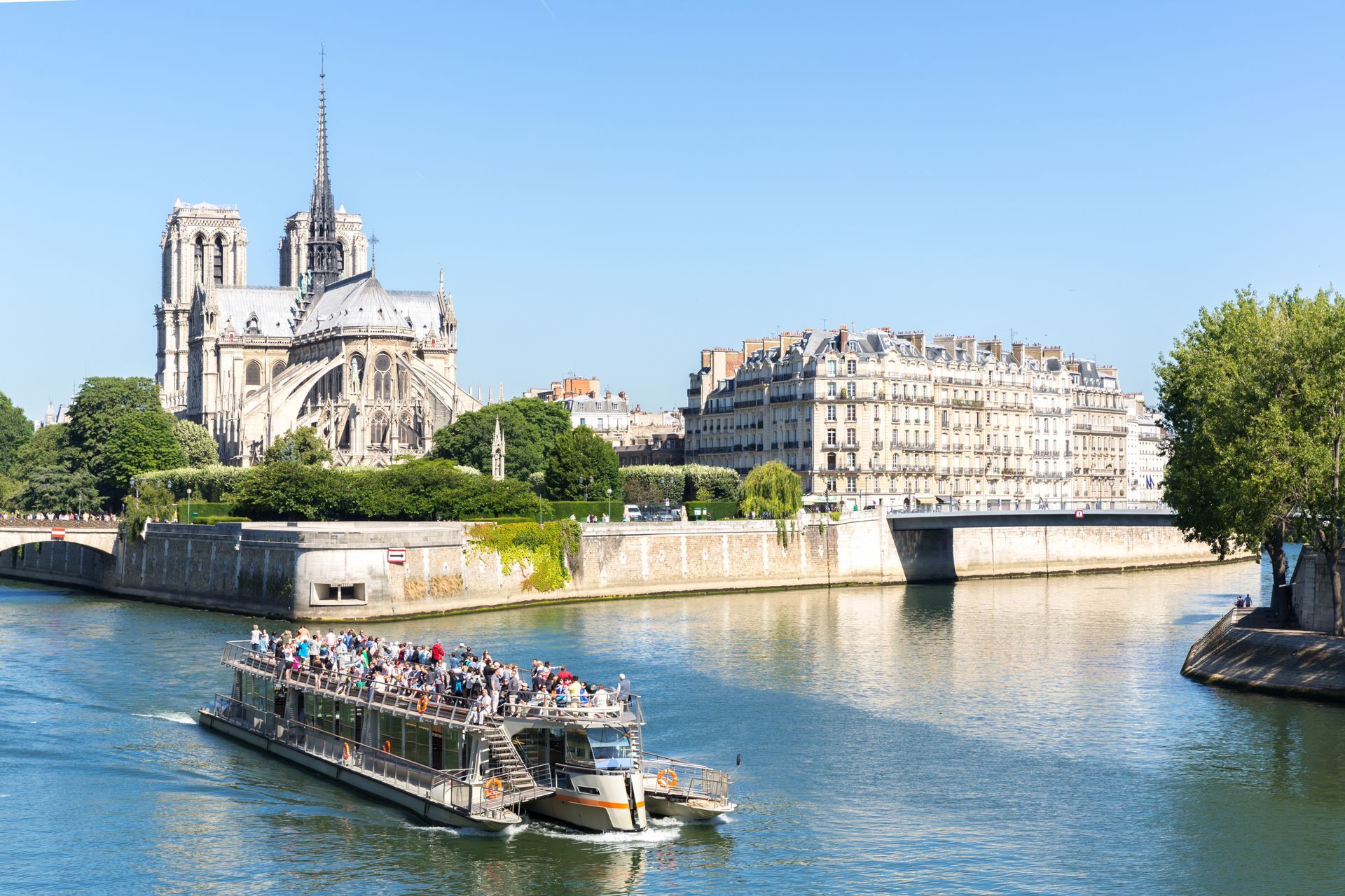 Notre Dame Cathedral overlooking a boat on the Seine River in Paris, France, on a sunny day. Notre Dame Cathedral overlooking a boat on the Seine River in Paris, France, on a sunny day.