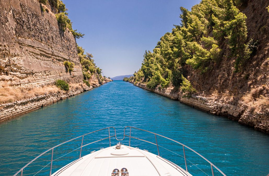 Boat navigating the Corinth Canal, Greece. Emerald water, steep rock walls, blue sky. Boat navigating the Corinth Canal, Greece. Emerald water, steep rock walls, blue sky.