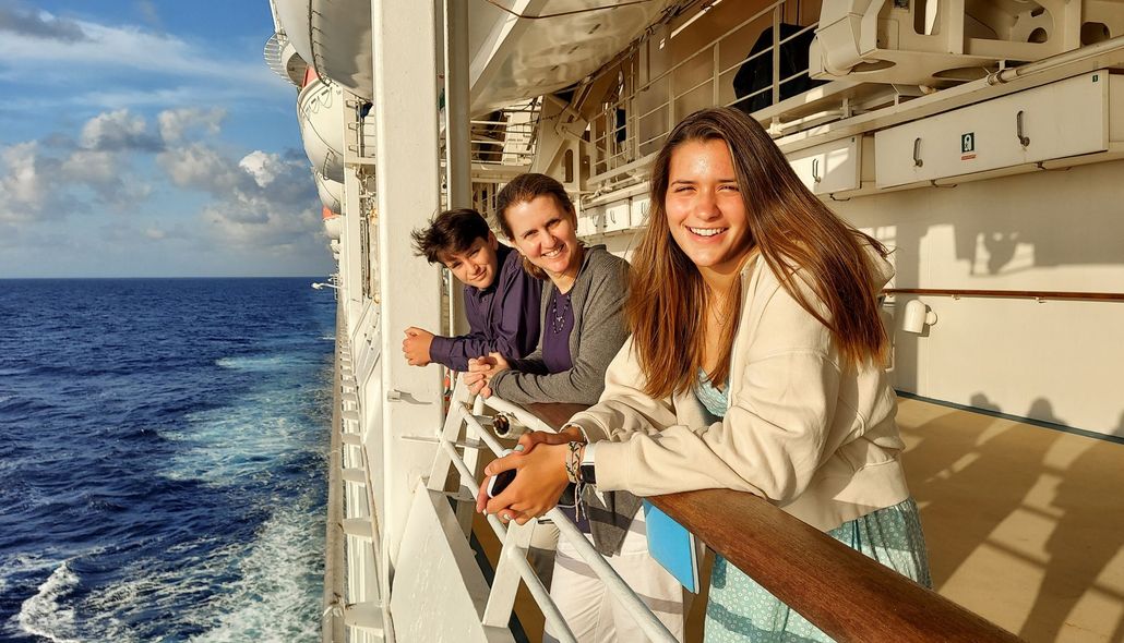 Three people smiling on a cruise ship deck, looking at the ocean. Three people smiling on a cruise ship deck, looking at the ocean.