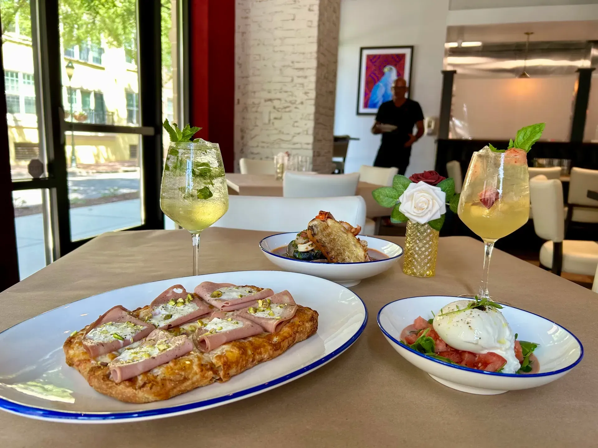 Table with food and drinks in a restaurant, with a person in the background.