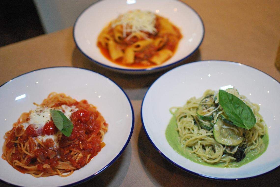 Three bowls of pasta with different sauces and garnishes.
