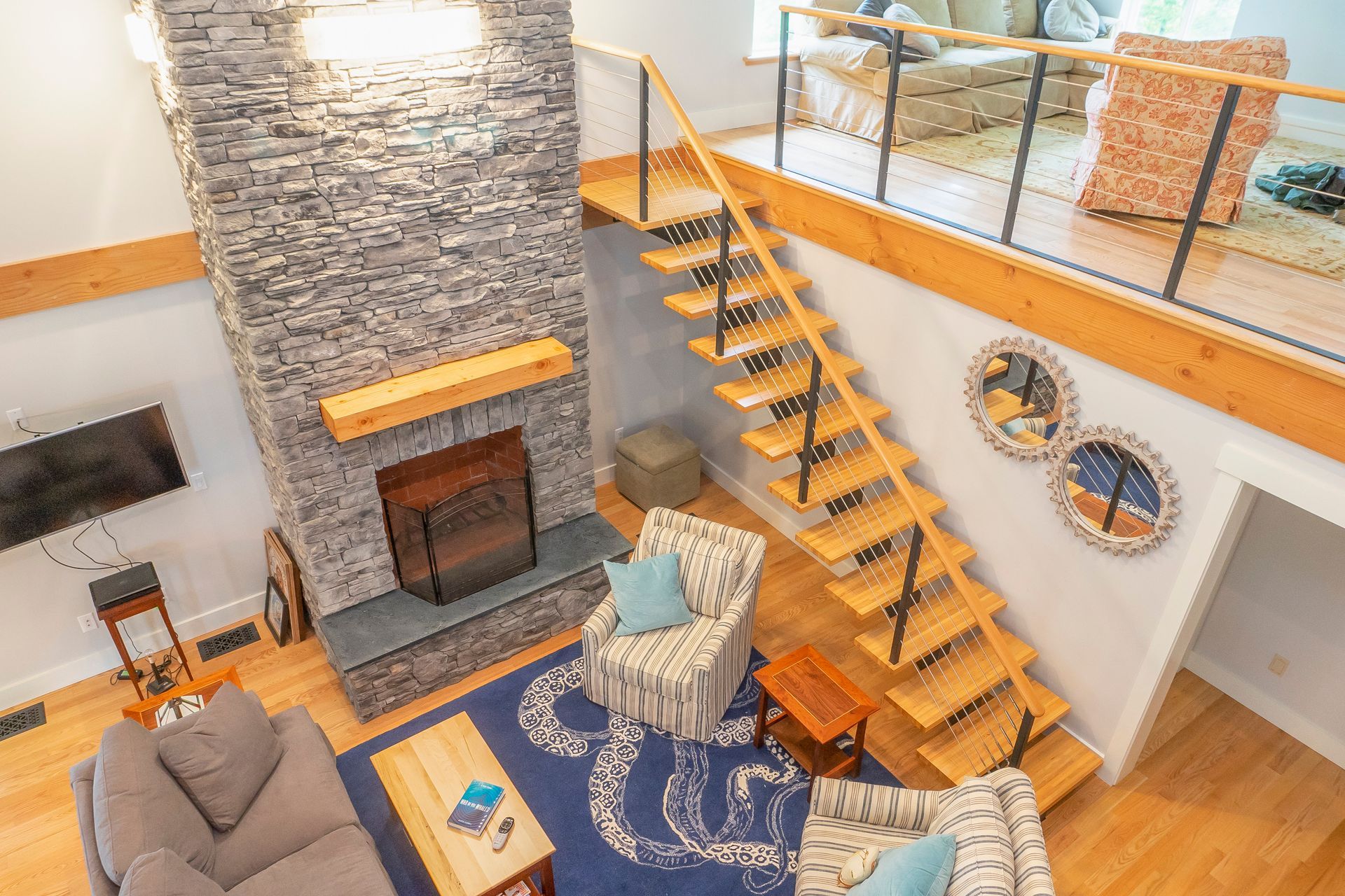 An aerial view of a living room with a fireplace and stairs.