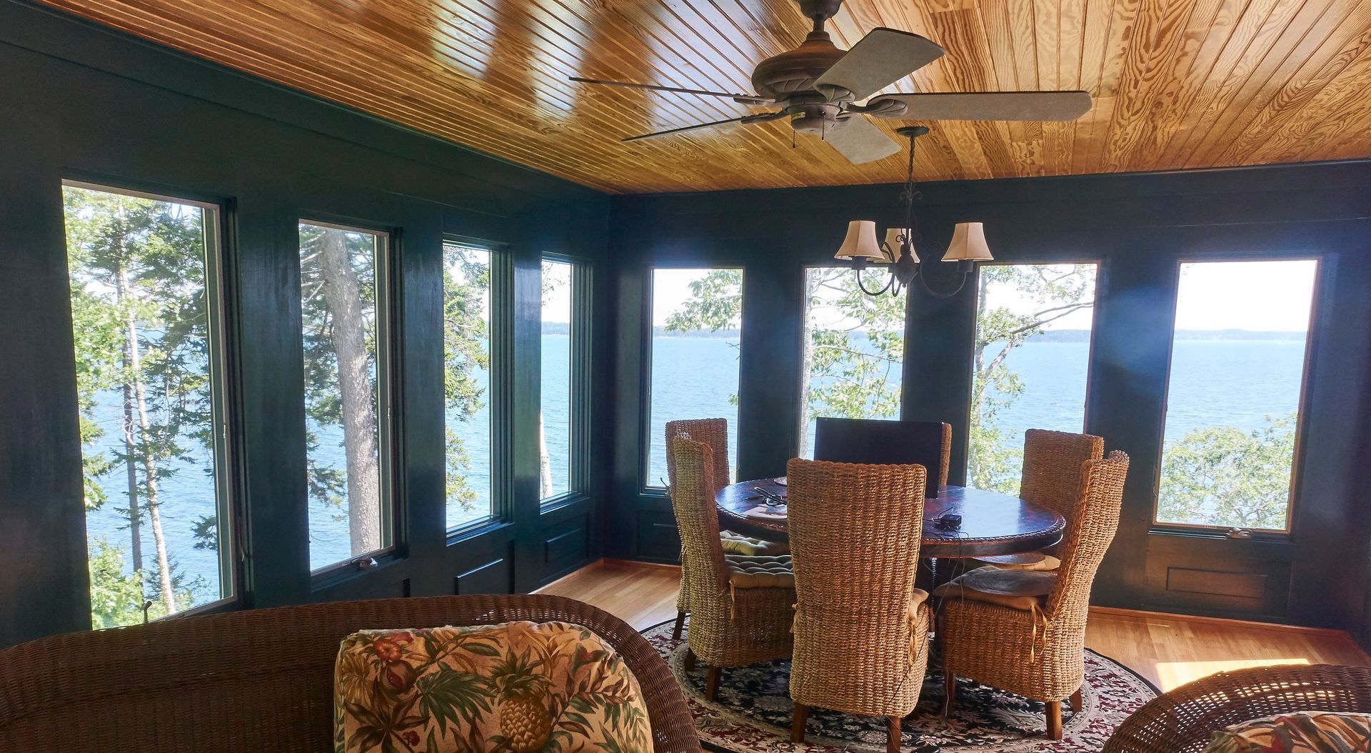 A nely built addition room with a table and chairs and a ceiling fan and an ocean view in Belfast, Maine
