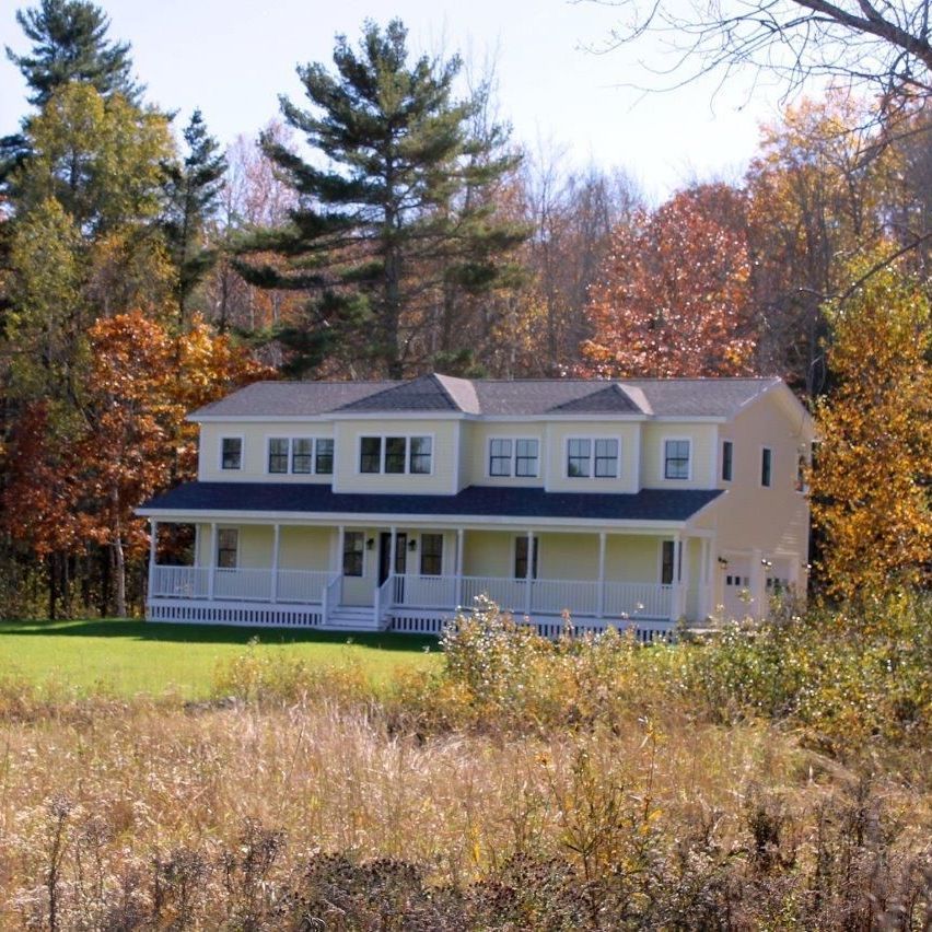 A house with a large porch in the middle of a field