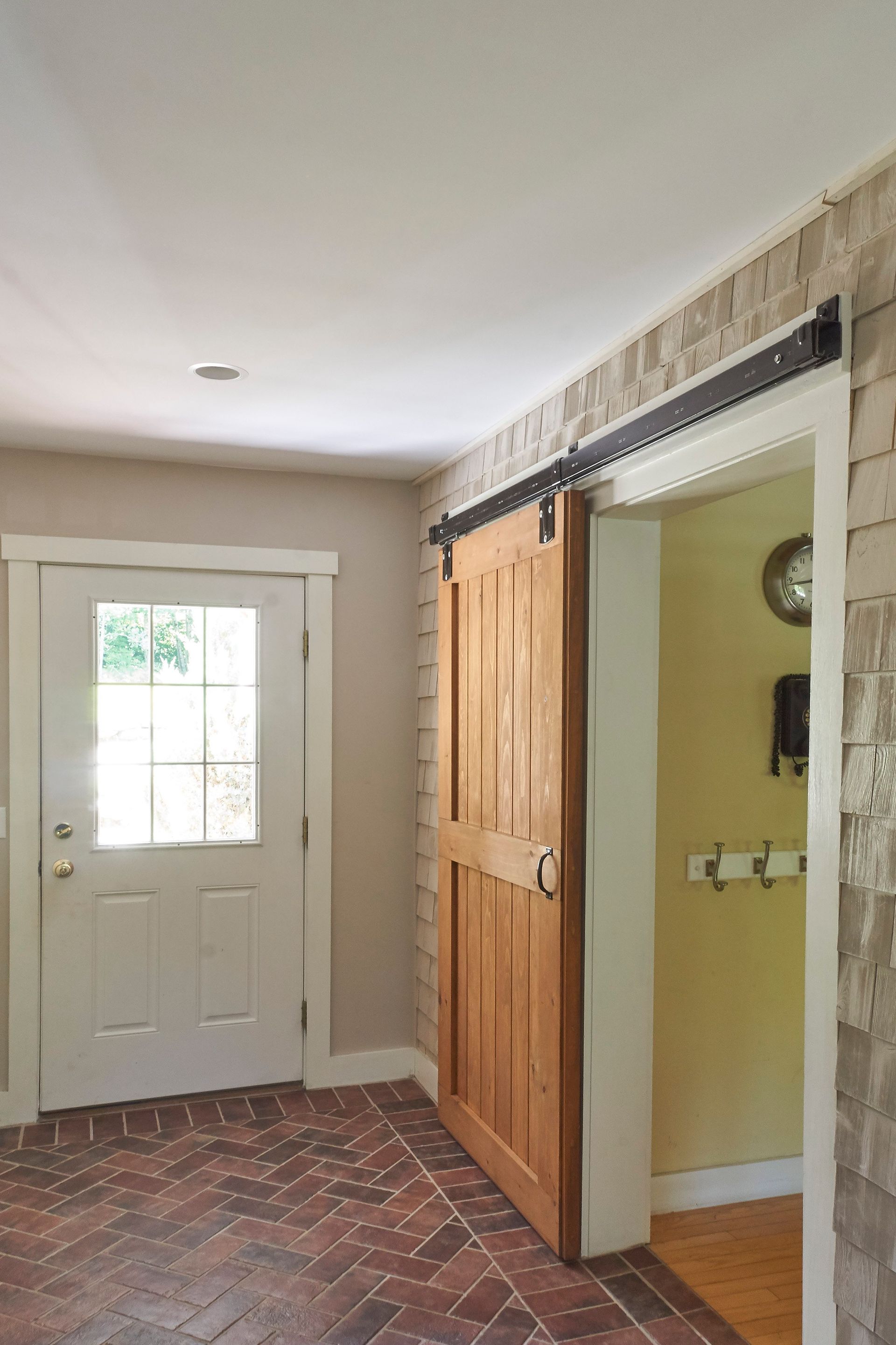 A hallway with a sliding barn door and a white door.