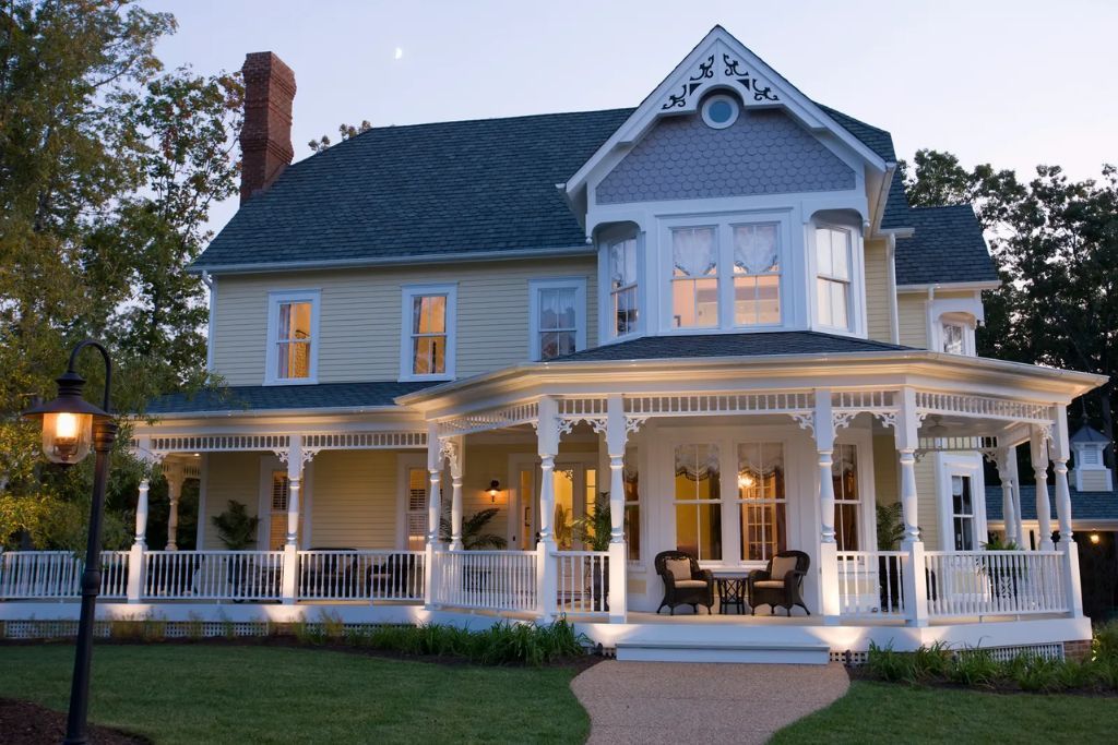 A large house with a large porch is lit up at night