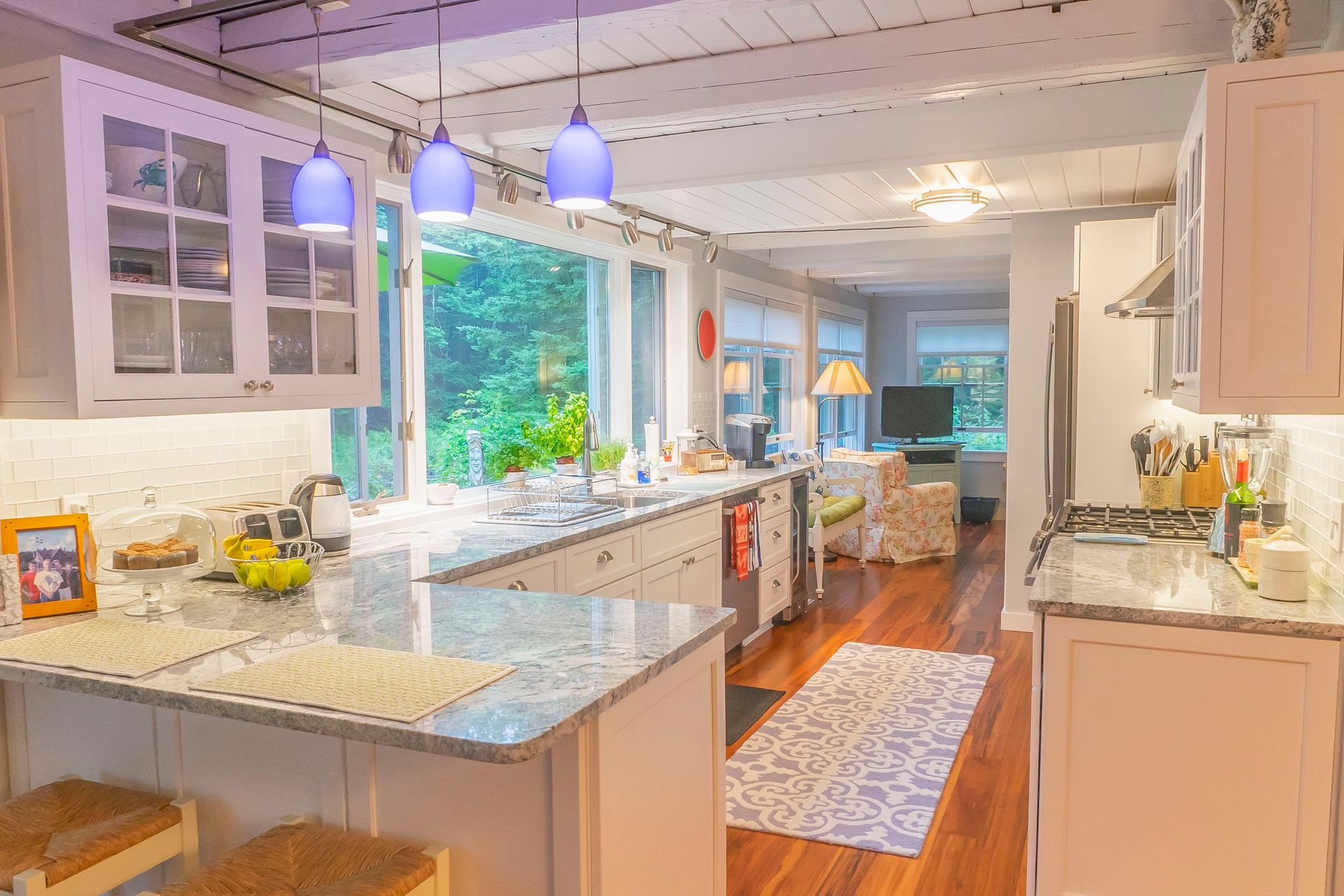 A kitchen with white cabinets , granite counter tops , and a large island.