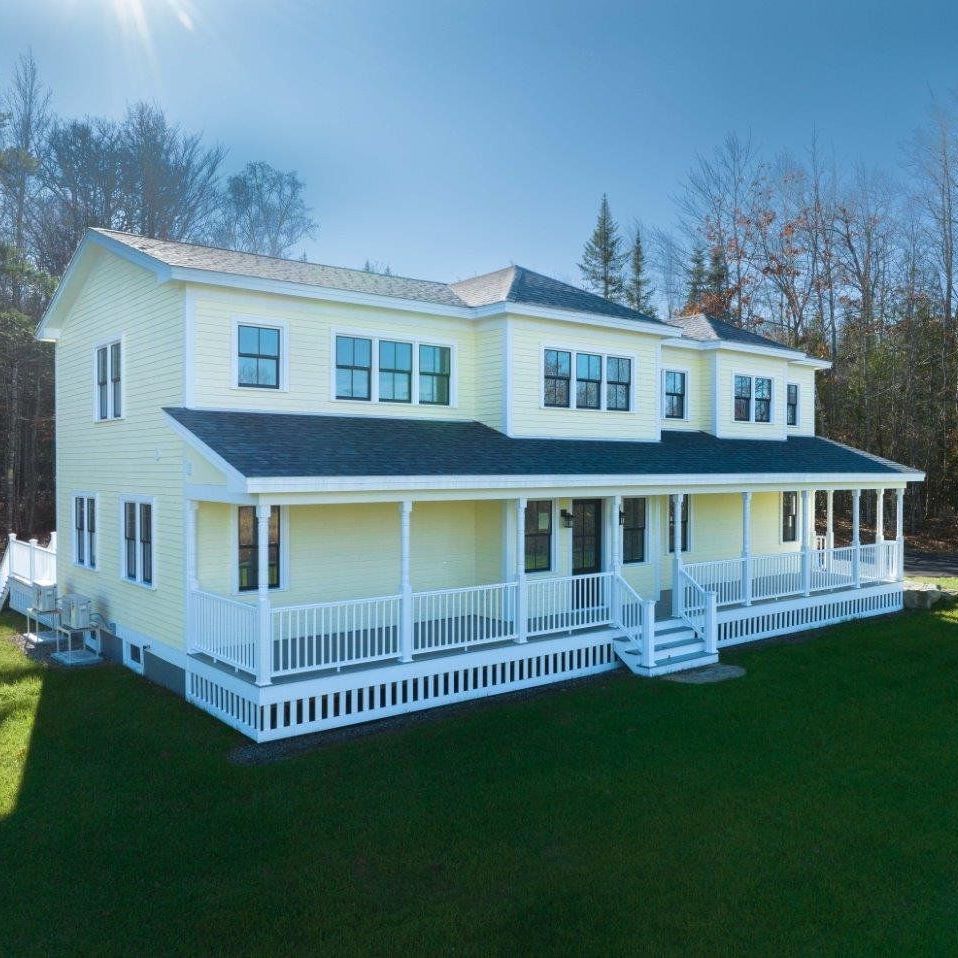 A large green house with a balcony and a fence in front of it.