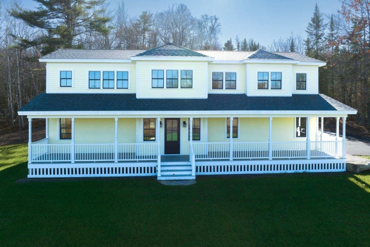 A large yellow house with a blue roof and a large porch.