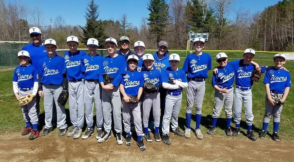 A group of young boys are posing for a picture on a baseball field.