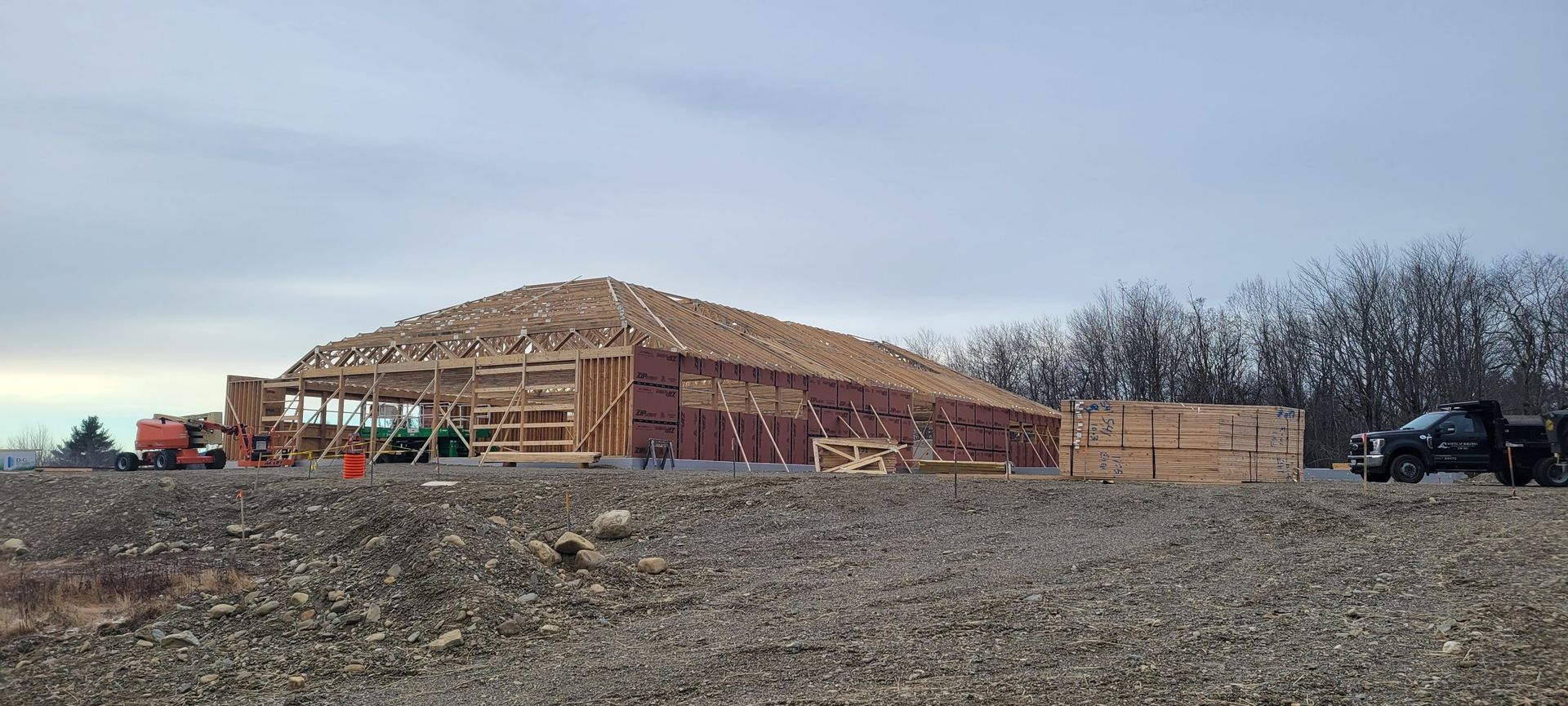 A large building is being built in a gravel lot.