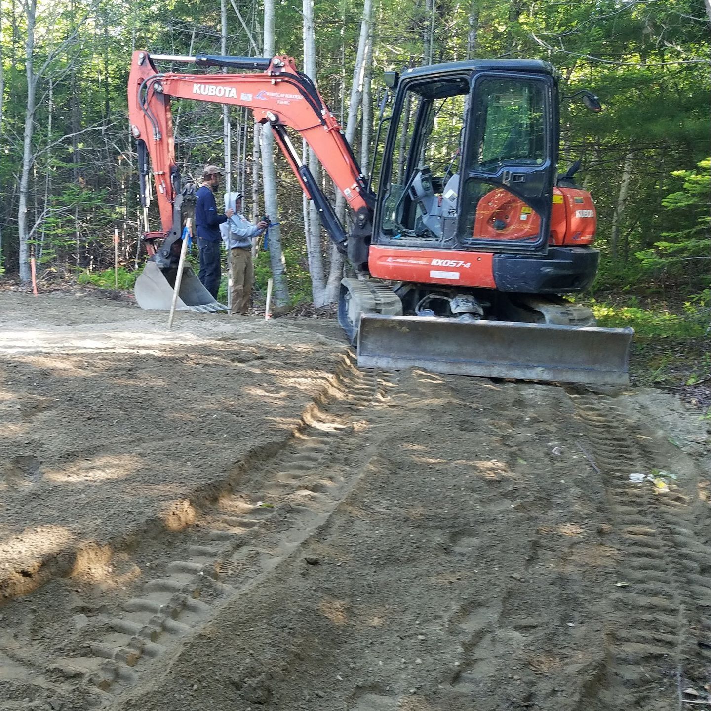A red and black excavator is digging in the dirt
