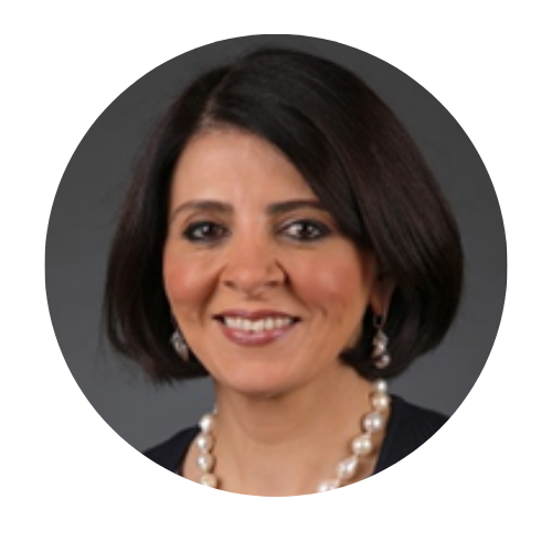 Smiling woman with short dark hair, pearl necklace, and earrings against a gray background