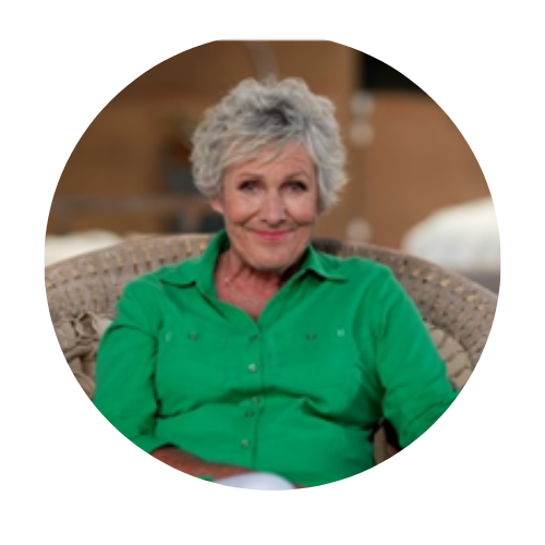 Smiling person in a bright green shirt sitting on a wicker chair indoors