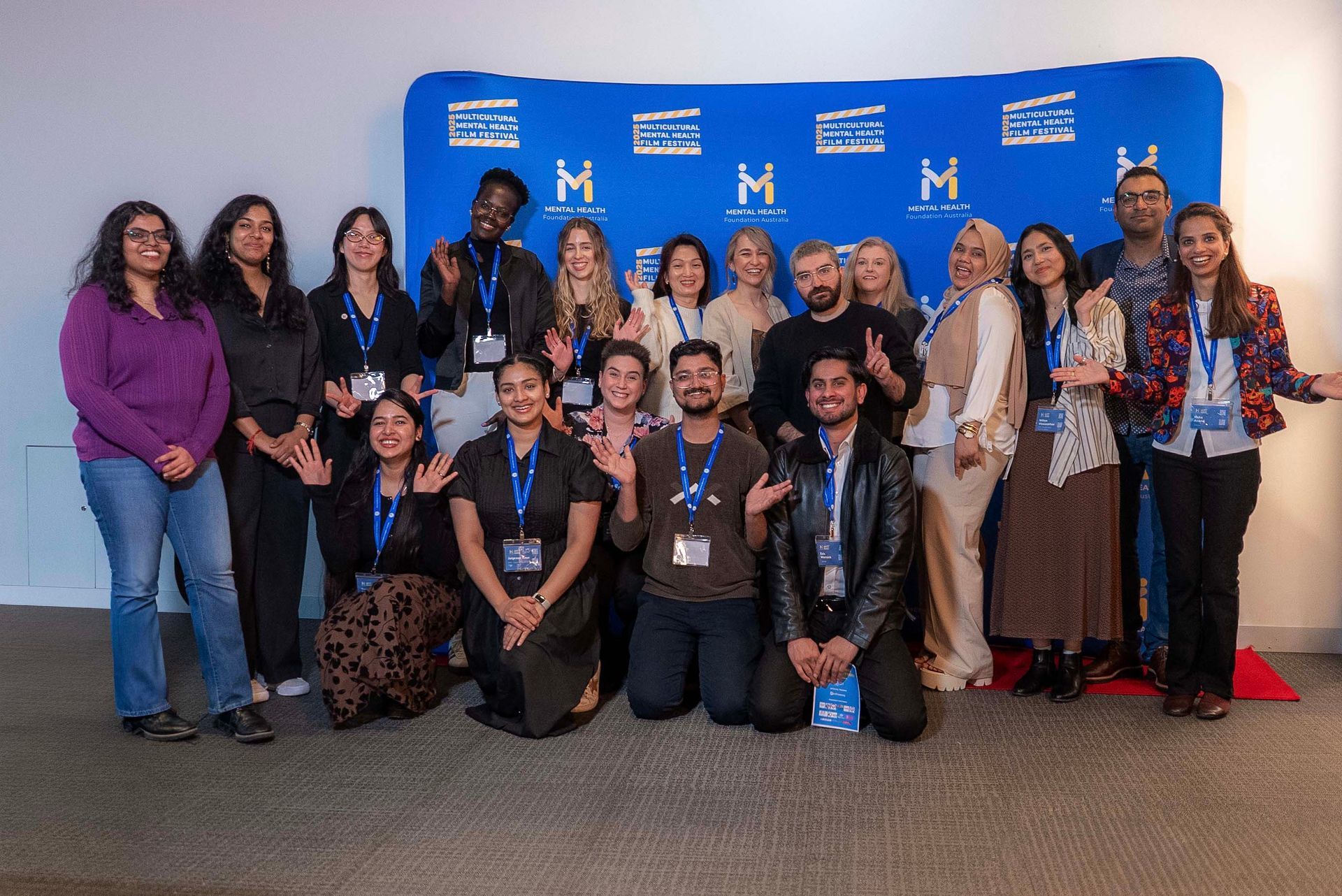 Group of people posing at an event in front of a blue backdrop with logos and badges on display.