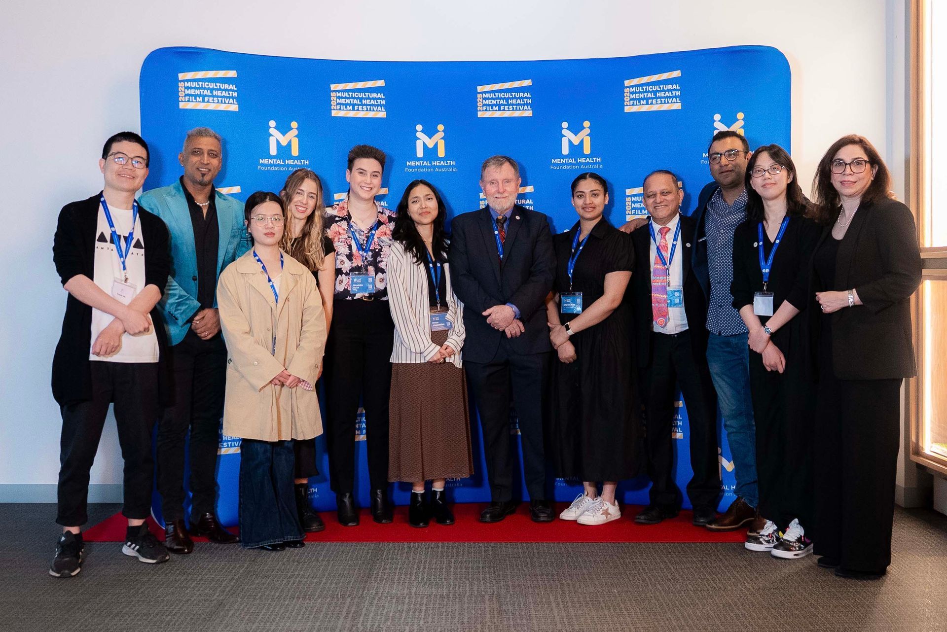 Group of people posing in front of a blue step-and-repeat backdrop at an event