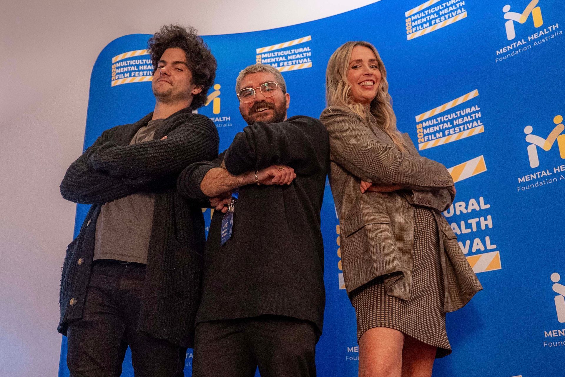 Three people pose with crossed arms in front of a blue Montreal Health Festival backdrop.