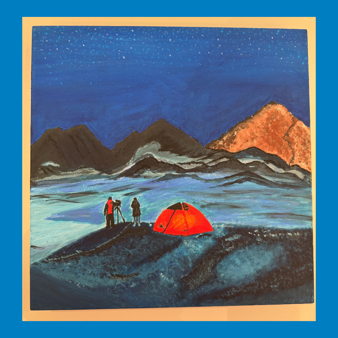 Campers beside a red tent on a dark rocky shore under blue sky and mountains at dusk