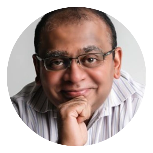 Smiling person wearing glasses, resting chin on hand, in a striped shirt against a light background