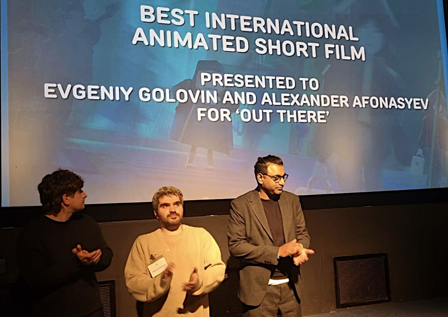 Award screen announcing Best International Animated Short Film as three people stand on stage