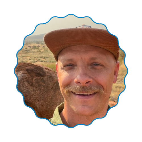 Smiling man in a brown hat taking a selfie in a desert landscape