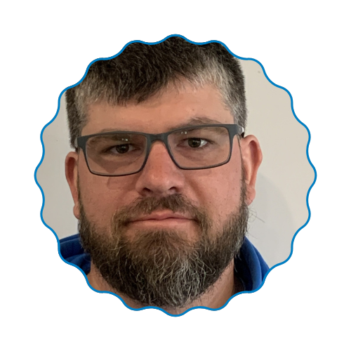 Portrait of a bearded man wearing glasses, framed by a blue scalloped border