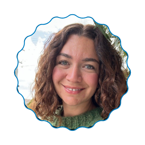 Smiling woman with curly hair in a blue scalloped frame, wearing a green sweater