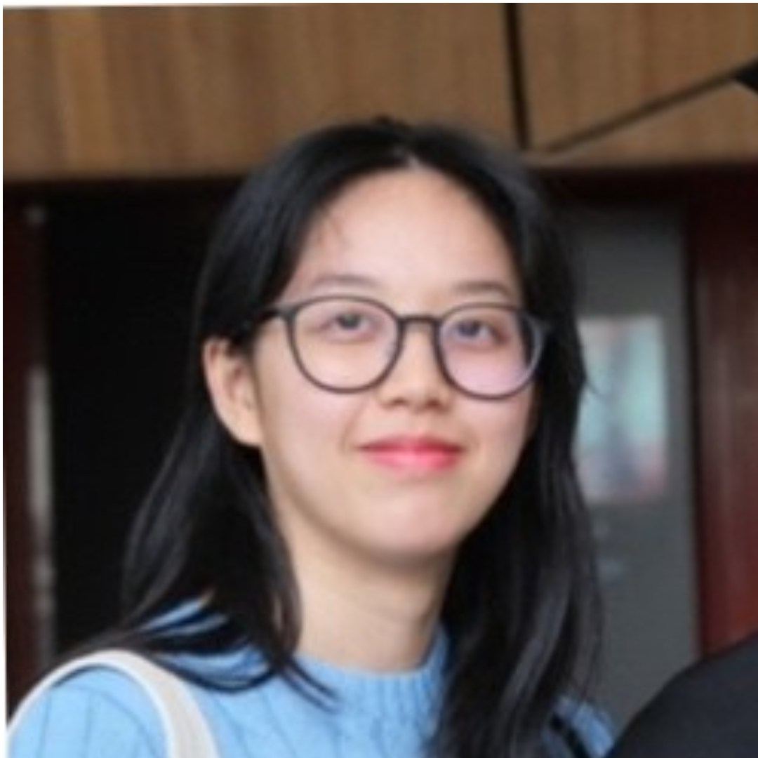 Woman with glasses and long black hair, wearing a light blue shirt, smiling indoors.