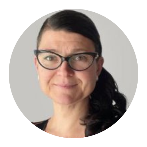 Portrait of a person with dark hair and glasses, smiling against a light gray background