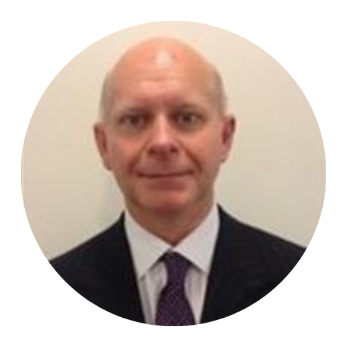Headshot of a bald man in a dark suit, white shirt, and purple tie against a plain background