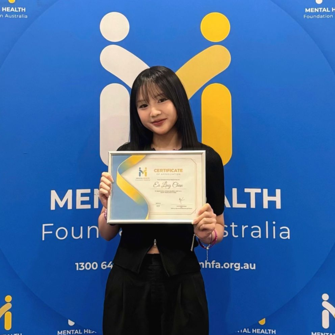 Woman holding a certificate in front of a blue Mental Health Foundation Australia backdrop