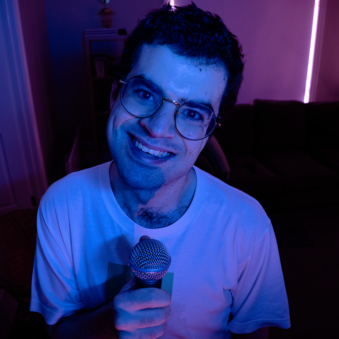 Person smiling and holding a microphone under blue and purple lighting indoors