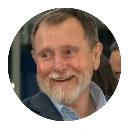 Smiling bearded man in a suit jacket, looking to the side.