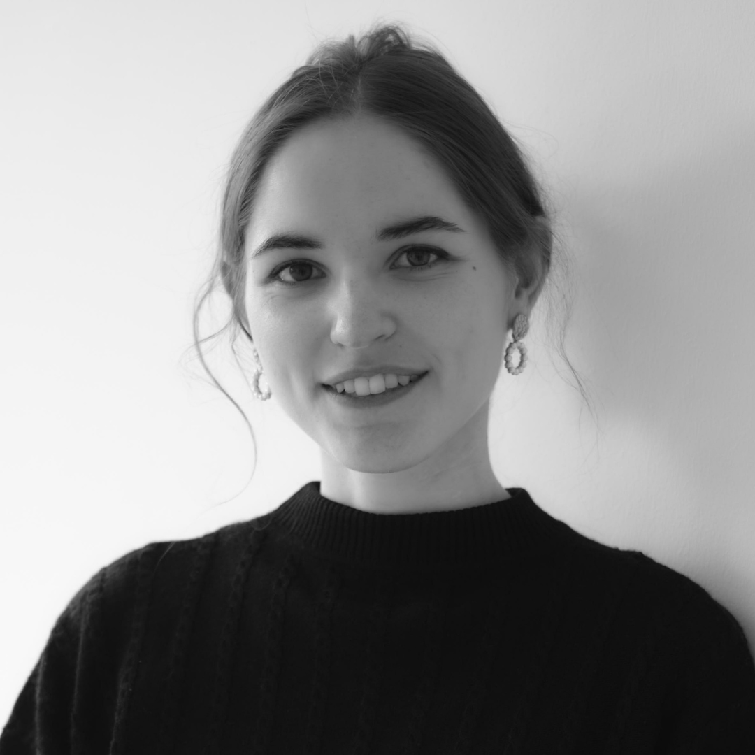 Portrait of a smiling person in a black sweater against a plain light background