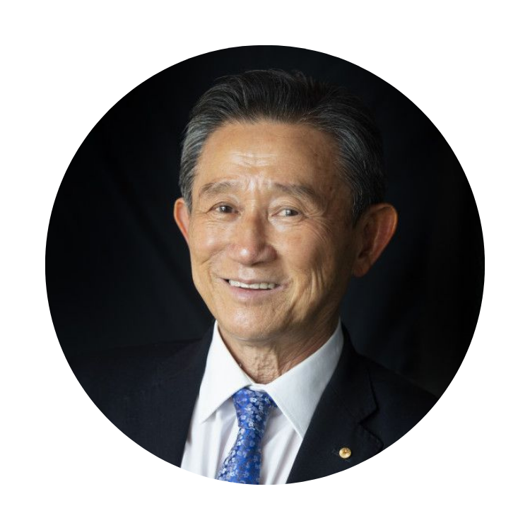 Smiling man in a dark suit and blue tie against a black background