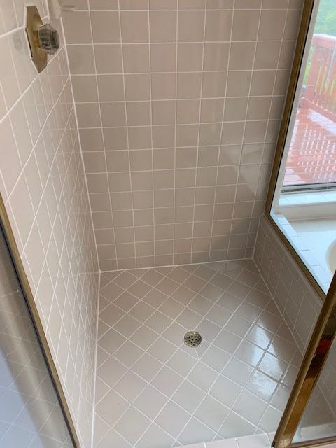 A bathroom with white tiles and a walk in shower.