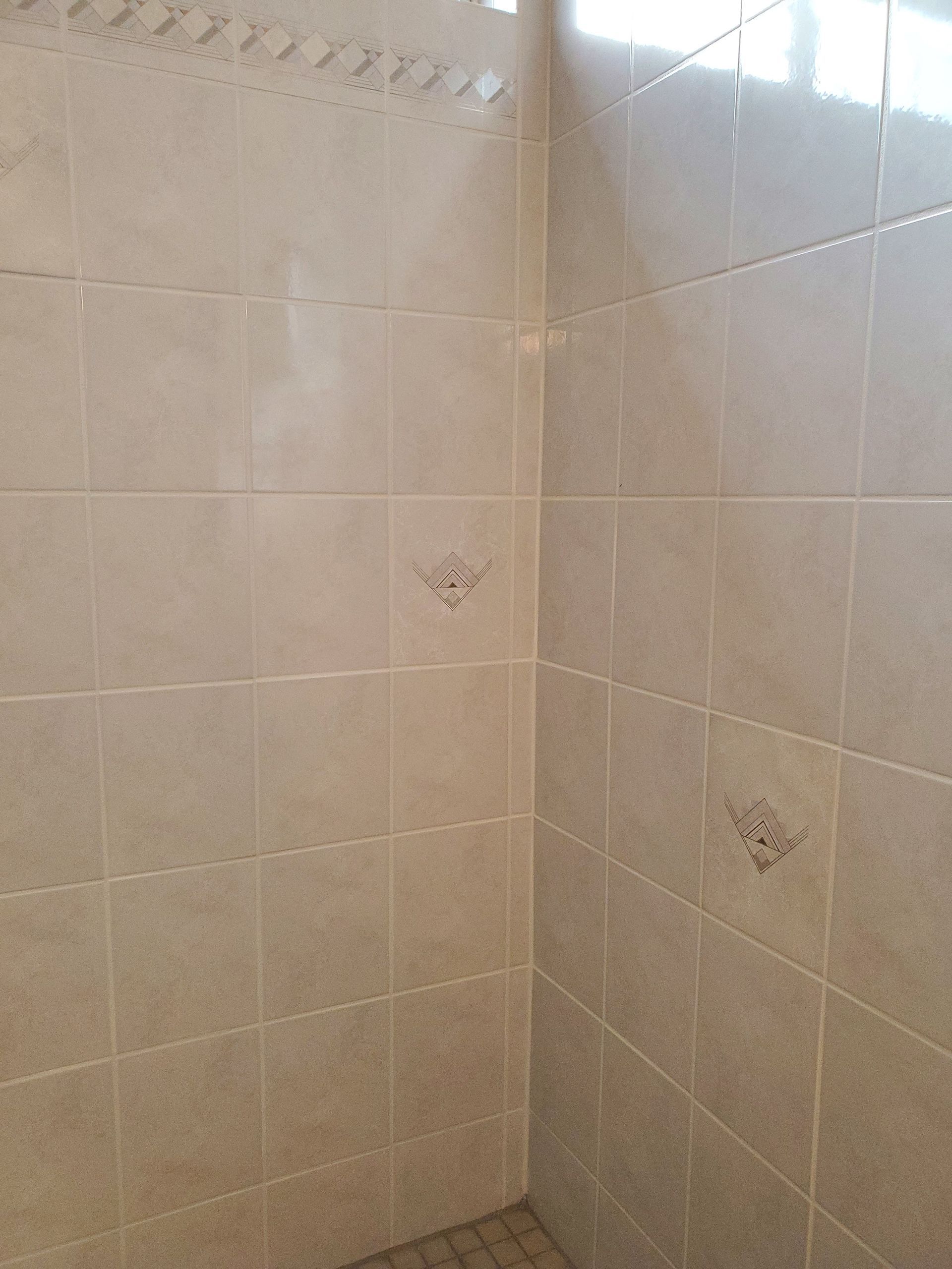 A bathroom with white tiles and a walk in shower.