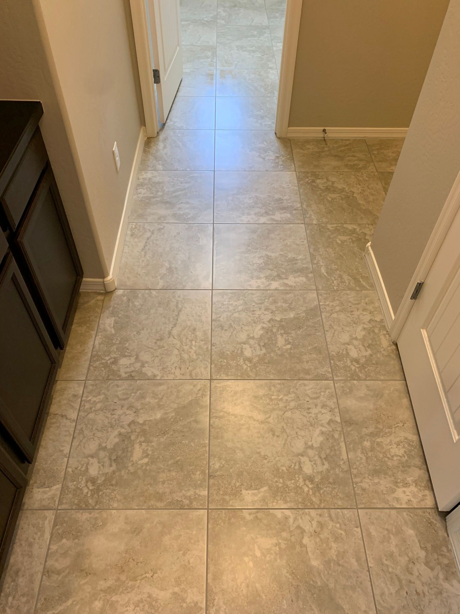 A hallway with tile floors and a door leading to a bathroom.