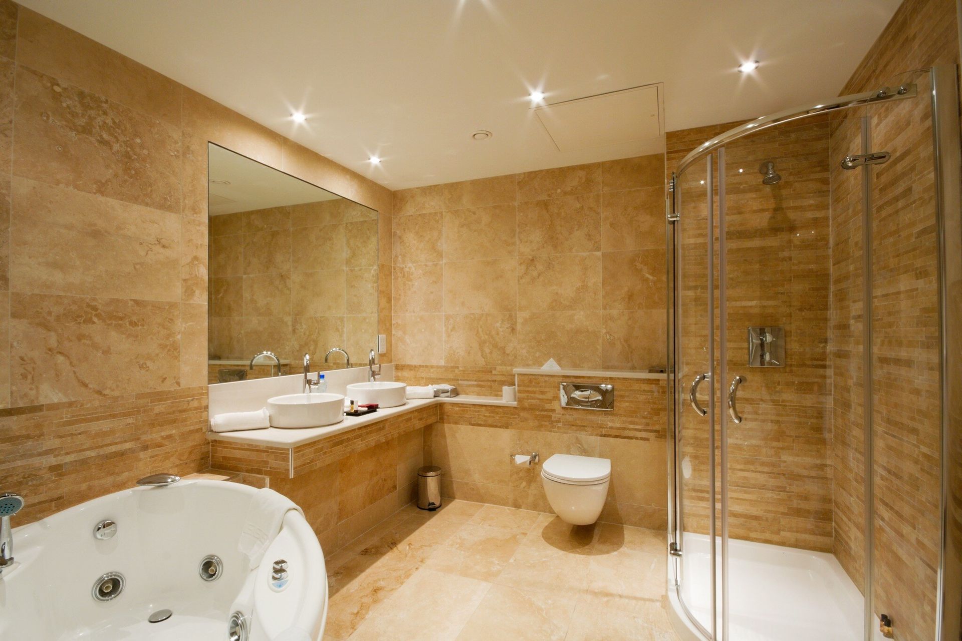 A bathroom with a jacuzzi tub , toilet , sink and shower.