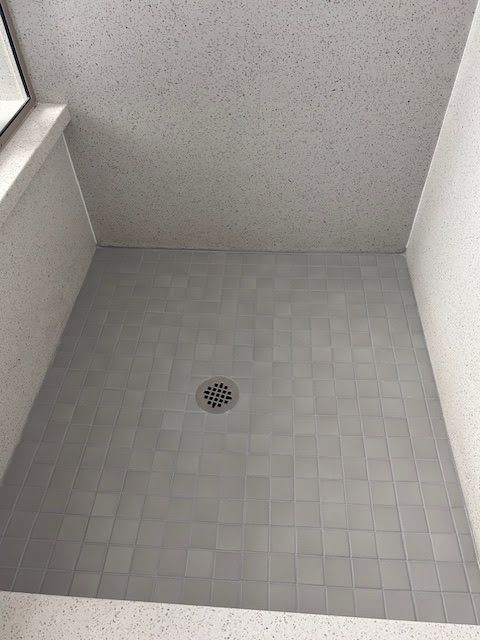 A shower stall with a drain in the middle of it.