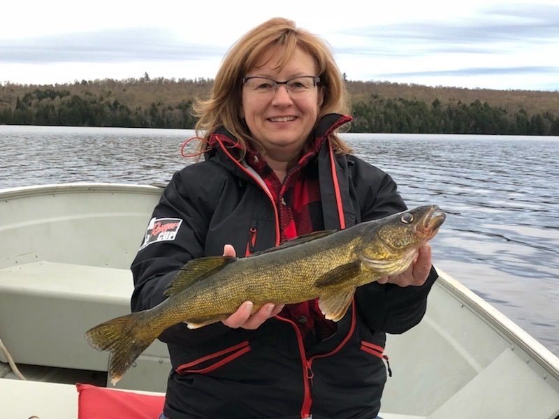 Smiling angler holding a large fish on a boat at a lake
