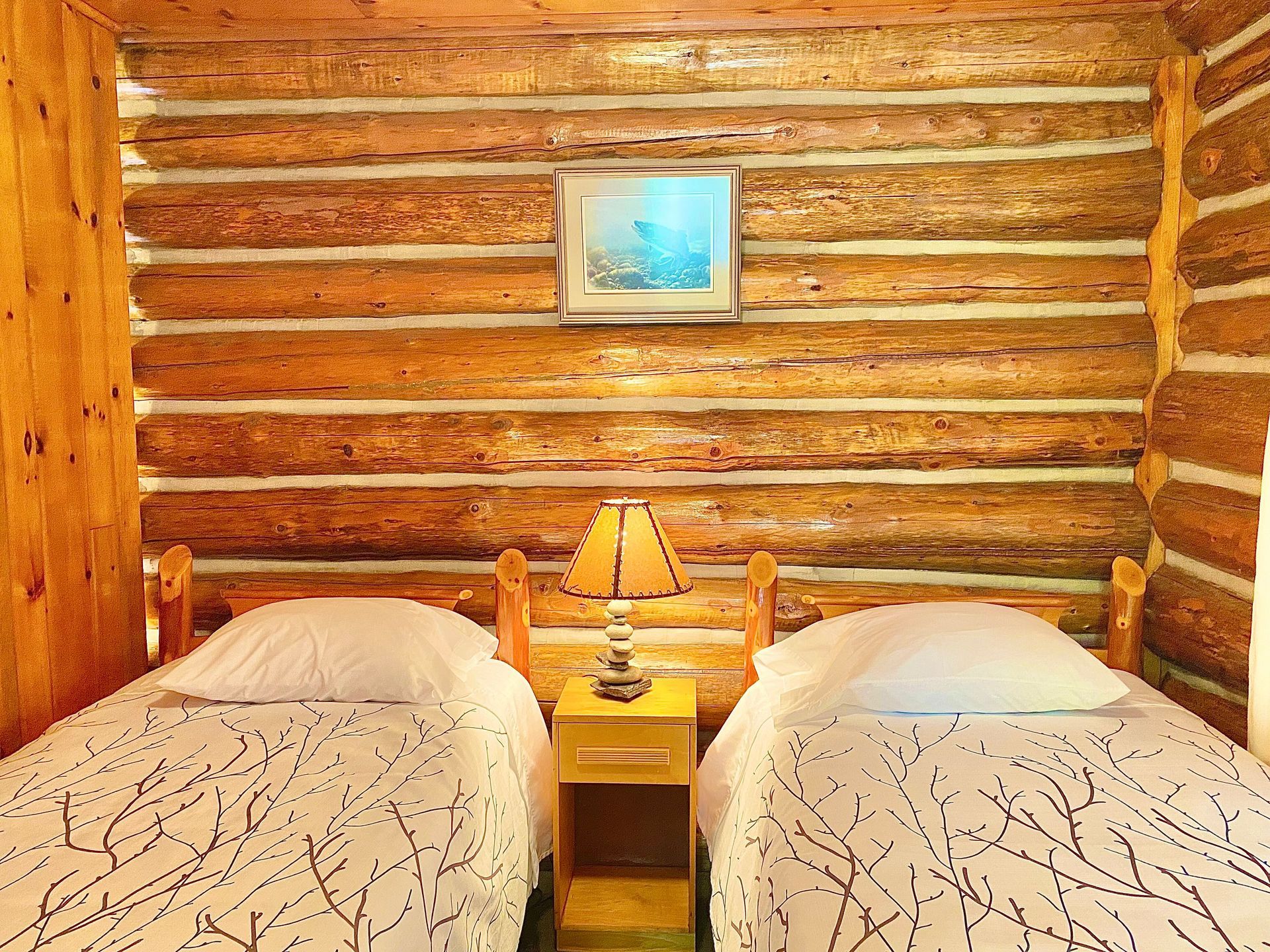 A bedroom in White Pine cottage with two beds and a painting on the wall.