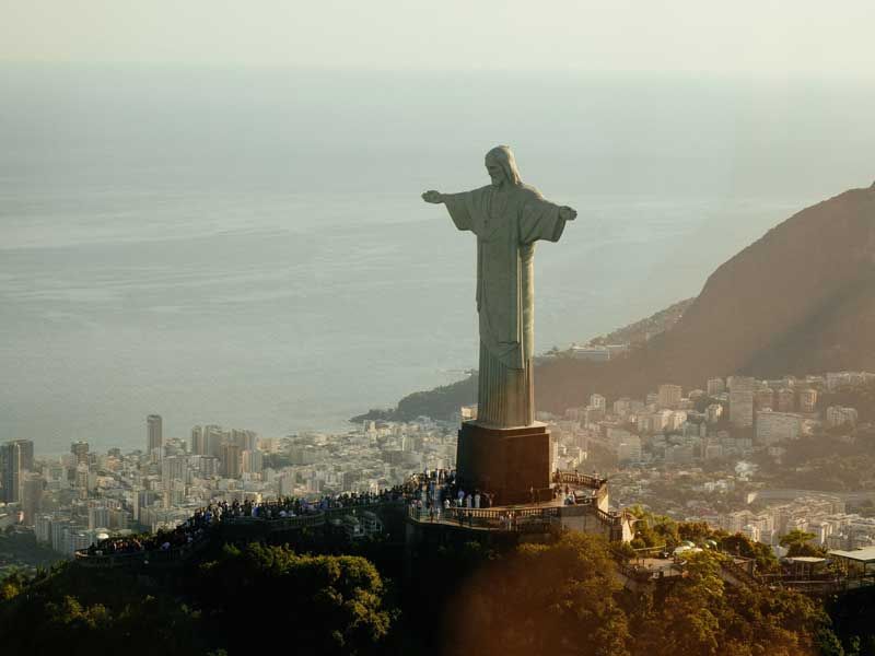 A estátua do Cristo Redentor ergue-se no topo do Morro do Corcovado, com vista para a cidade do Rio de Janeiro e para o oceano.