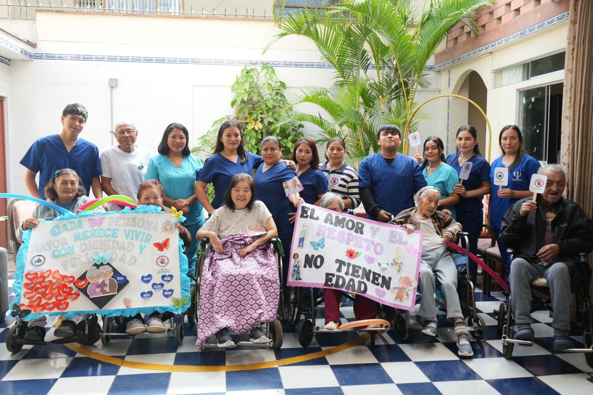 Grupo sosteniendo carteles contra la discriminación por edad en un luminoso patio interior